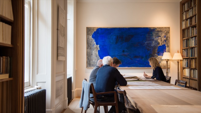 Advisors in a meeting at a long table beneath a large blue painting